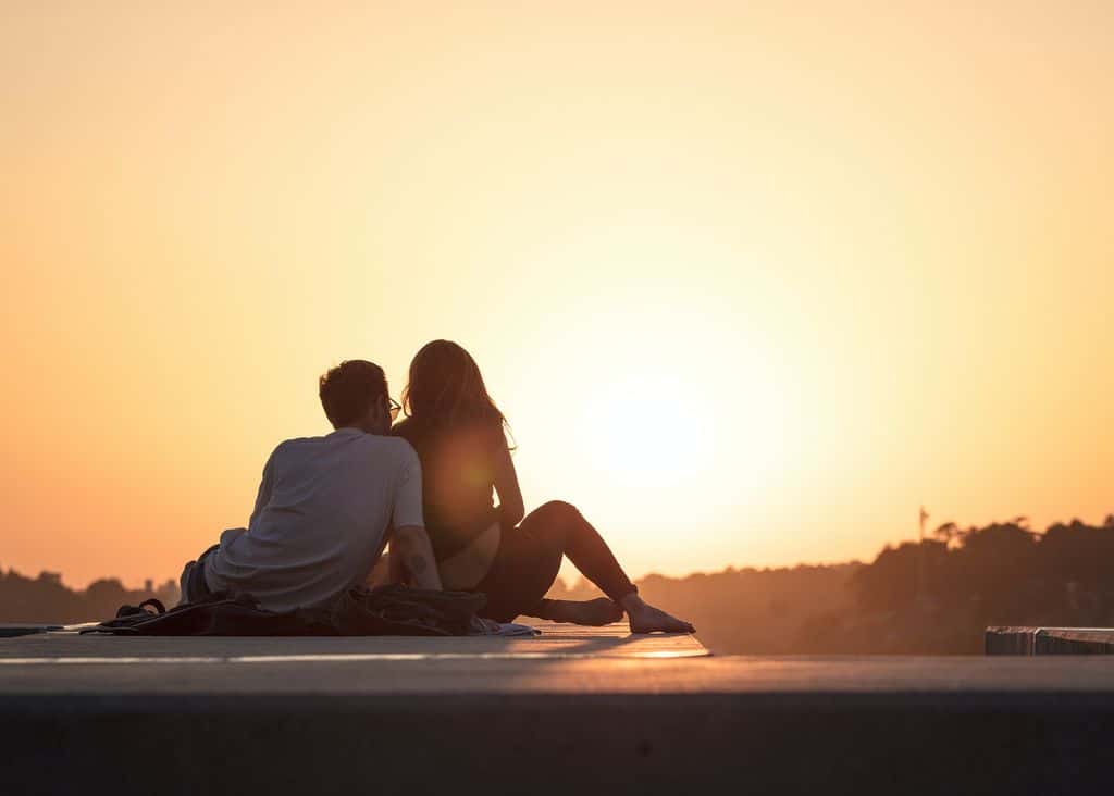 A couple sitting on a bridge at sunset, a perfect image for an article on classic nicknames for your beau