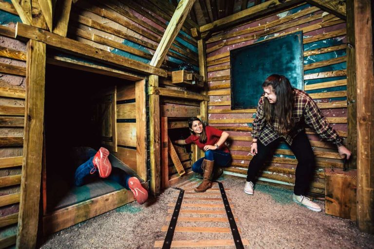 Two people in a wooden house with a train track - Ensuring safety and supervision in a kids' escape room setup