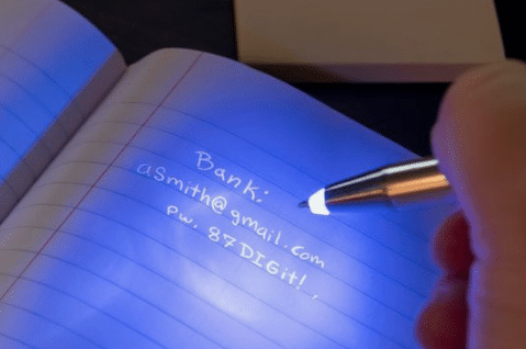 A child playing the 'Invisible Ink Adventure Game for Kids' writes on a notebook with a pen