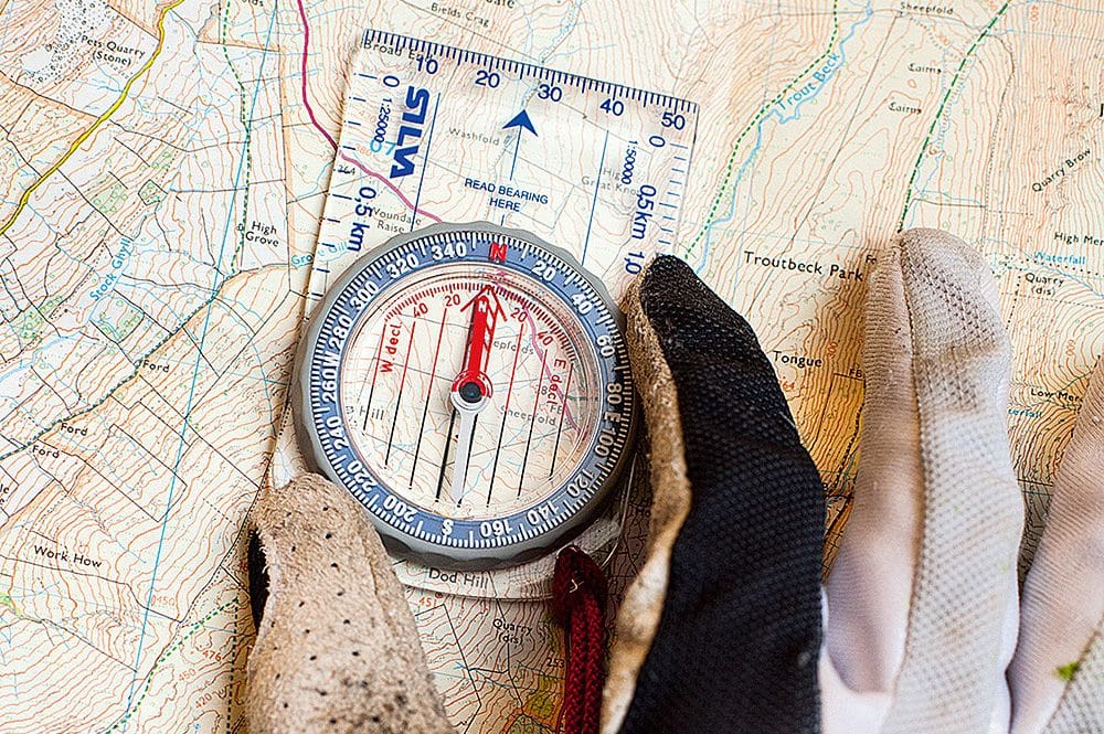 A compass and gloves on a map, aiding in learning map navigation while playing