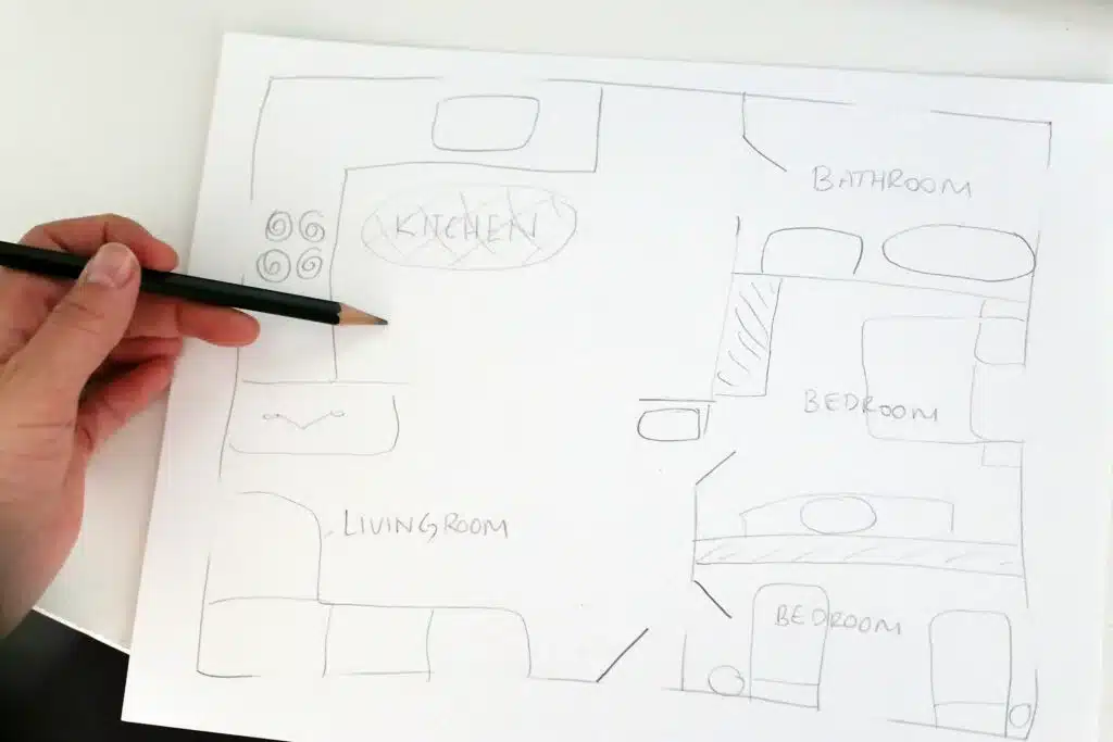 A person meticulously sketching a floor plan on paper, creating a detailed map of the house