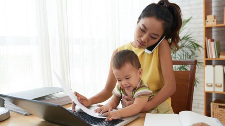 She holds her baby while using a laptop