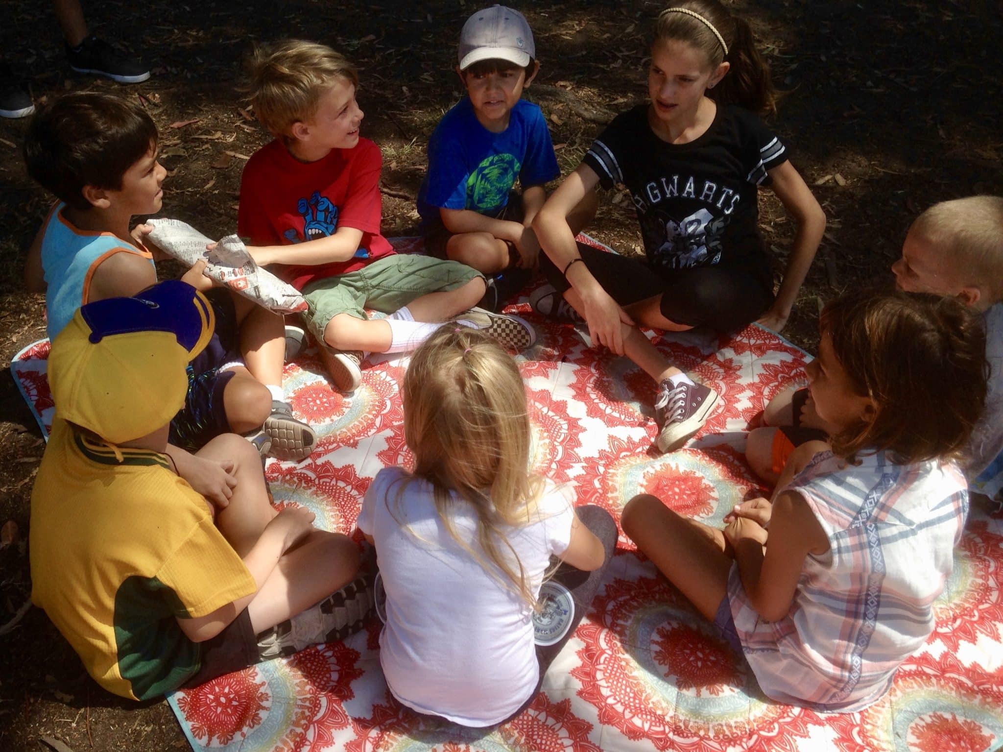 A group of children sitting on a blanket, enjoying a game of "Passing the Parcel