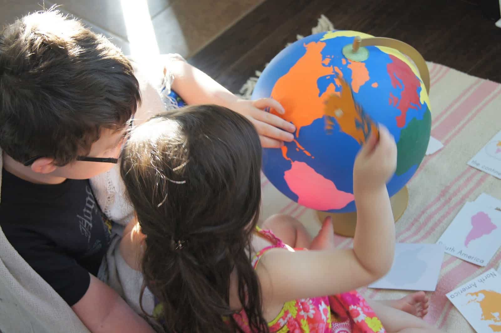 a globe, exploring the world together. They are pasting a map on it.