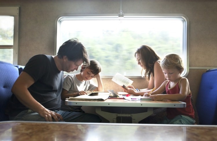 A family gathered around a table, engrossed in a book, exploring the art of storytelling through maps
