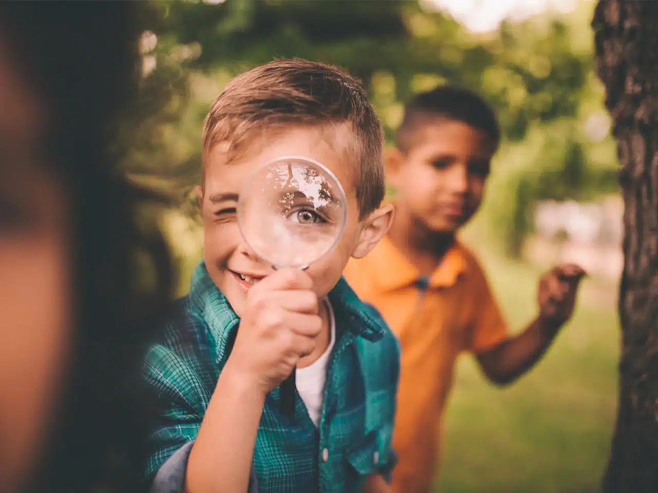 During a scavenger hunt in a public park, a boy holds a magnifying glass, exploring his surroundings with curiosity