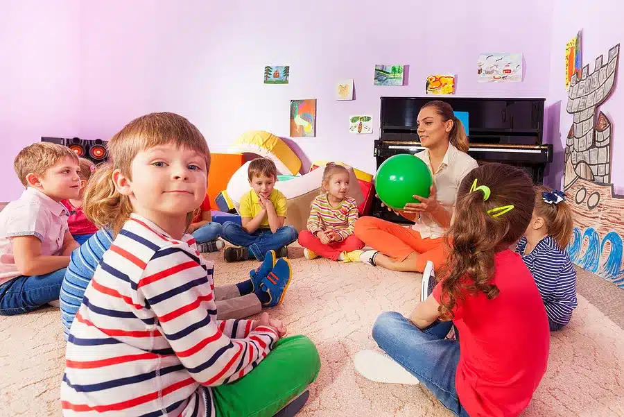 A group of children sitting on the floor in a classroom, engaged in a lively session of Storytime Hot Potato