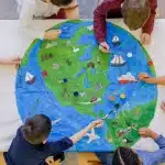 Children drawing on a paper globe, exploring global cultures through games