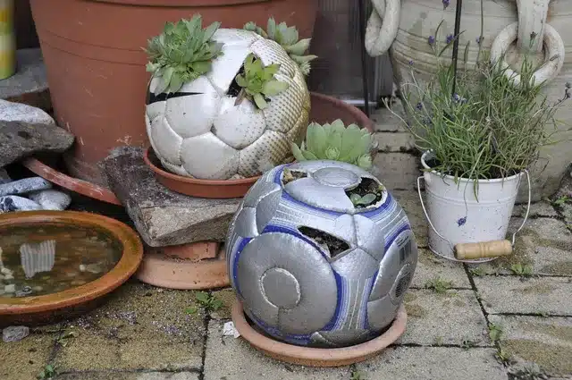 Two planters with plants on a brick patio, showcasing upcycling projects