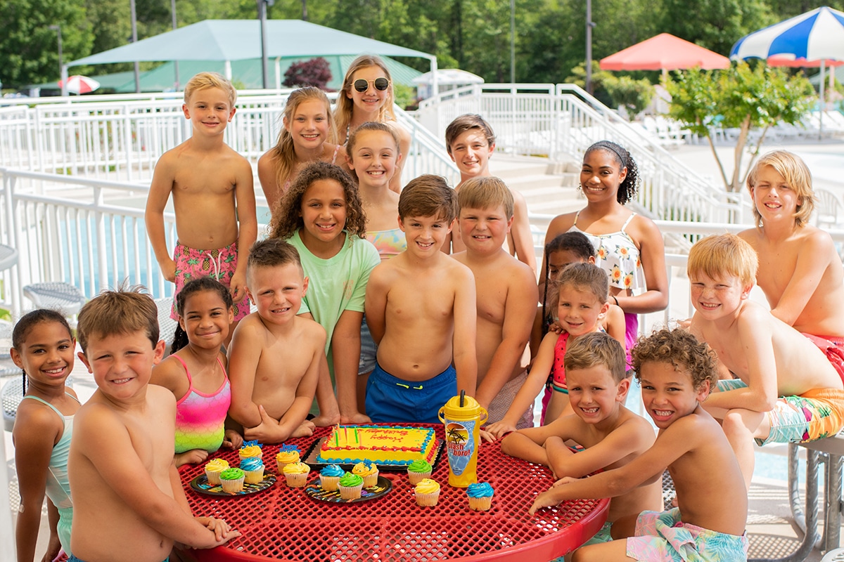 A joyful group of children smiling and posing for a photo at a pool in a water park.