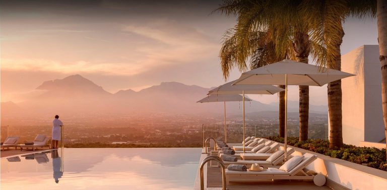 A serene pool area with lounge chairs and umbrellas, offering a breathtaking view of the mountains