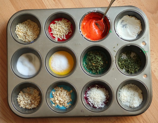 A muffin pan filled with colorful ingredients, perfect for baking or creating art with textured finger paintings