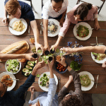 A group of people sitting around a table with food Description automatically generated