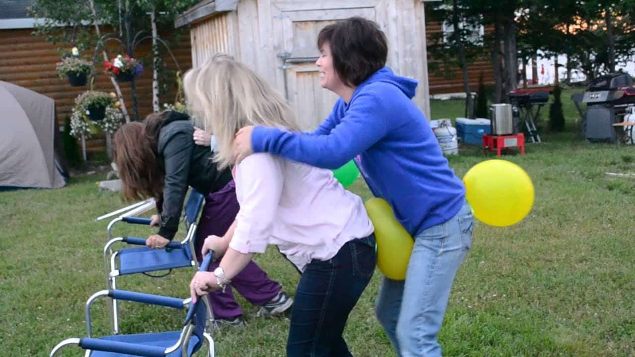 Two women playing Balloon Pop Relay in yard.