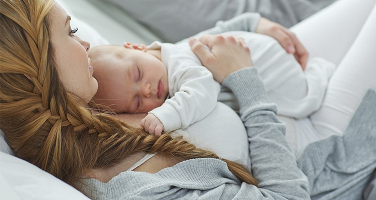  A woman holding her baby on a bed, 